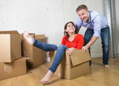 happy American couple unpacking moving in new house playing with