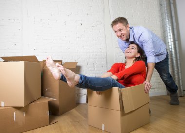 happy American couple unpacking moving in new house playing with