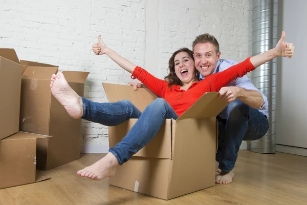Feliz pareja americana desempacar mudanza en nueva casa jugando con —  Fotos de Stock