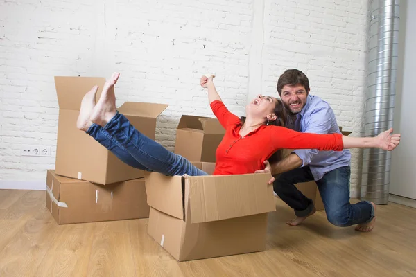 Happy American couple unpacking moving in new house playing with — Stockfoto