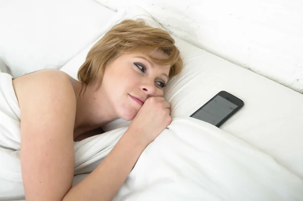 Mujer atractiva joven en la cama solo con el teléfono móvil como compañero de dormir en Internet y el concepto de adicción al teléfono inteligente —  Fotos de Stock