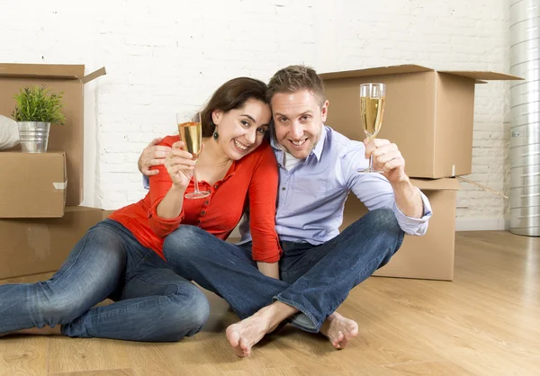 Heureux couple américain assis sur le sol déballer ensemble célébrer avec champagne toast déménagement dans une nouvelle maison — Photo