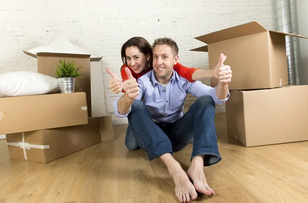 Jonge gelukkige paar zittend op de vloer samen vieren bewegen in nieuwe platte huis of appartement — Stockfoto