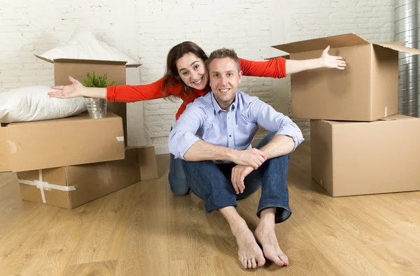 Young happy couple sitting on floor together celebrating moving in new flat house or apartment — Stock Photo, Image