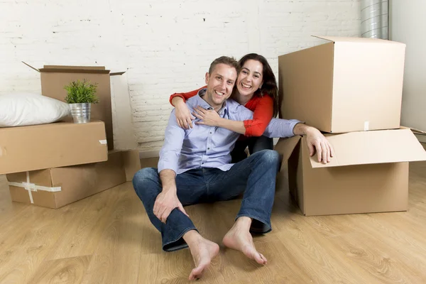 Jonge gelukkige paar zittend op de vloer samen vieren bewegen in nieuwe platte huis of appartement — Stockfoto