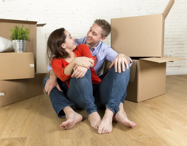 Feliz pareja sentada en el suelo celebrando la mudanza en una casa o apartamento nuevo —  Fotos de Stock