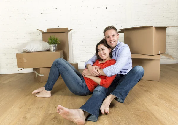 Gelukkige paar zittend op de vloer vieren bewegen in nieuwe platte huis of appartement — Stockfoto