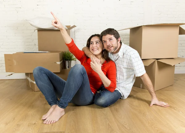 Gelukkige paar zittend op de vloer vieren bewegen in nieuwe platte huis of appartement — Stockfoto