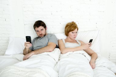 Genç evli çift yatakta birbirlerini ilişki iletişim sorunları görmezden cep telefonlarını kullanarak