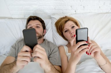 Genç evli çift yatakta birbirlerini ilişki iletişim sorunları görmezden cep telefonlarını kullanarak