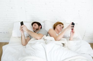 Genç evli çift yatakta birbirlerini ilişki iletişim sorunları görmezden cep telefonlarını kullanarak