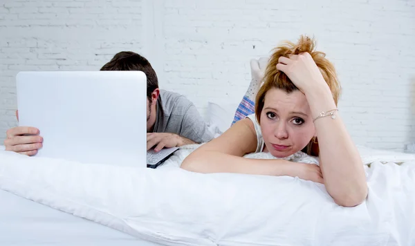 Aantrekkelijke vrouw gevoel overstuur ontevreden en gefrustreerd in bed met zijn echtgenoot terwijl de man werk op computer laptop het negeren van haar — Stockfoto