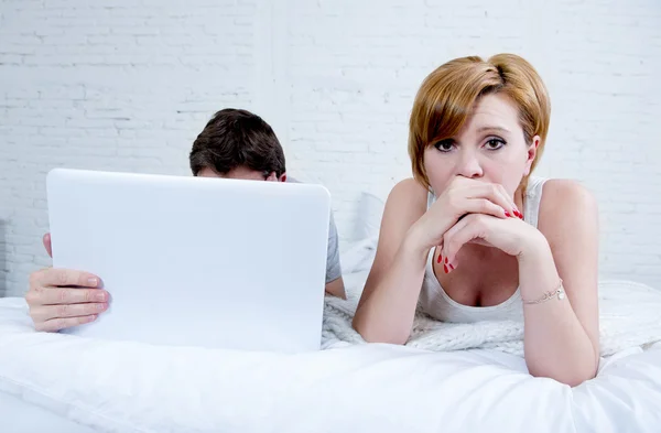 Aantrekkelijke vrouw gevoel overstuur ontevreden en gefrustreerd in bed met zijn echtgenoot terwijl de man werk op computer laptop het negeren van haar — Stockfoto