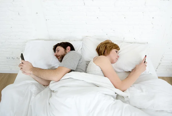 Jovem casal usando telefone celular na cama ignorando uns aos outros em problemas de comunicação de relacionamento — Fotografia de Stock