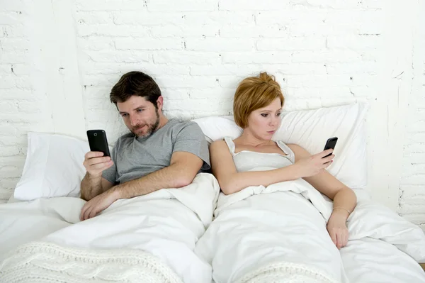 Jovem casal usando telefone celular na cama ignorando uns aos outros em problemas de comunicação de relacionamento — Fotografia de Stock