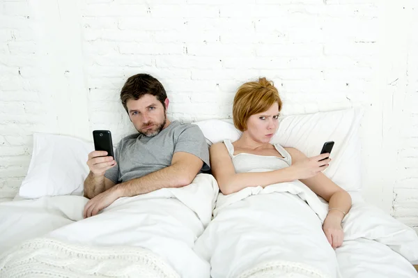 Young married couple using their mobile phone in bed ignoring each other in relationship communication problems — Stock Photo, Image