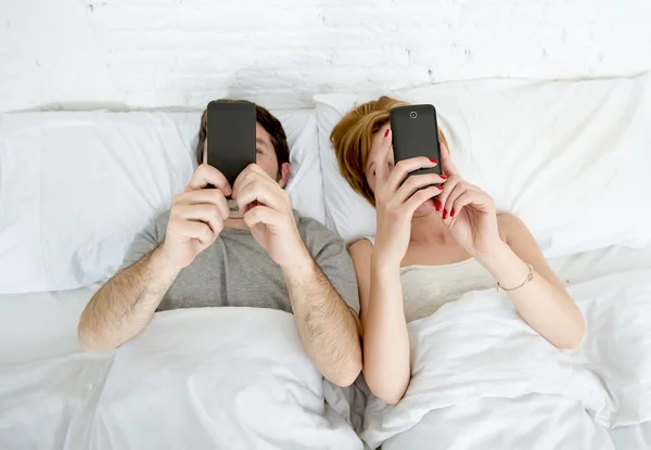 Jovem casal usando telefone celular na cama ignorando uns aos outros em problemas de comunicação de relacionamento — Fotografia de Stock