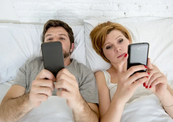 Pareja joven usando el teléfono móvil en la cama ignorándose unos a otros en problemas de comunicación relación —  Fotos de Stock