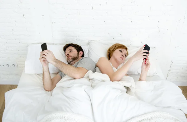 Jovem casal usando seu telefone celular na cama ignorando uns aos outros em problemas de comunicação de relacionamento — Fotografia de Stock