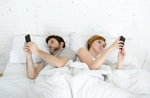 Jovem casal usando telefone celular na cama ignorando uns aos outros em problemas de comunicação de relacionamento — Fotografia de Stock