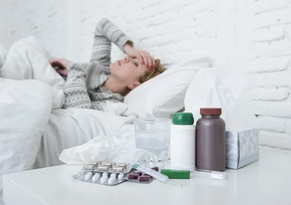 Больная женщина плохо себя чувствует лежа на кровати страдает от головной боли зимней простуды и вируса гриппа с лекарствами — стоковое фото