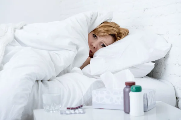 Mujer con nariz estornuda usando tejido en la cama que sufre de gripe por el virus del resfriado que tiene medicamentos —  Fotos de Stock