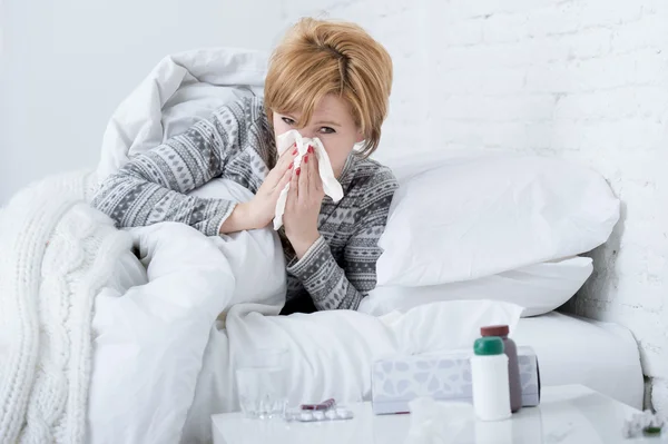 Mujer con estornudos nariz soplado en el tejido en la cama que sufre de resfriado síntomas del virus de la gripe que tiene medicamentos comprimidos —  Fotos de Stock