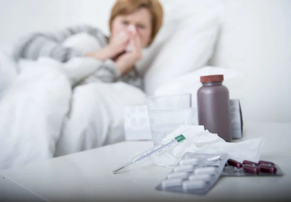 Donna con starnuti naso che soffia nel tessuto sul letto che soffre di sintomi del virus dell'influenza fredda con medicine compresse pillole — Foto Stock