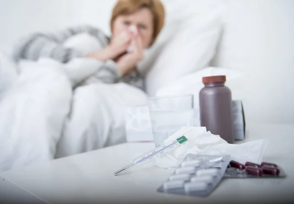 Woman with sneezing nose blowing in tissue on bed suffering cold flu virus symptoms having medicines tablets pills — Stock Photo, Image