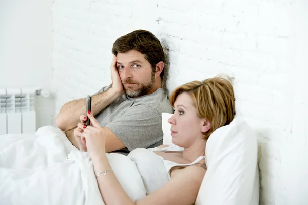 Par i sängen man frustrerad upprörd otillfredsställd medan hustru med mobiltelefon — Stockfoto