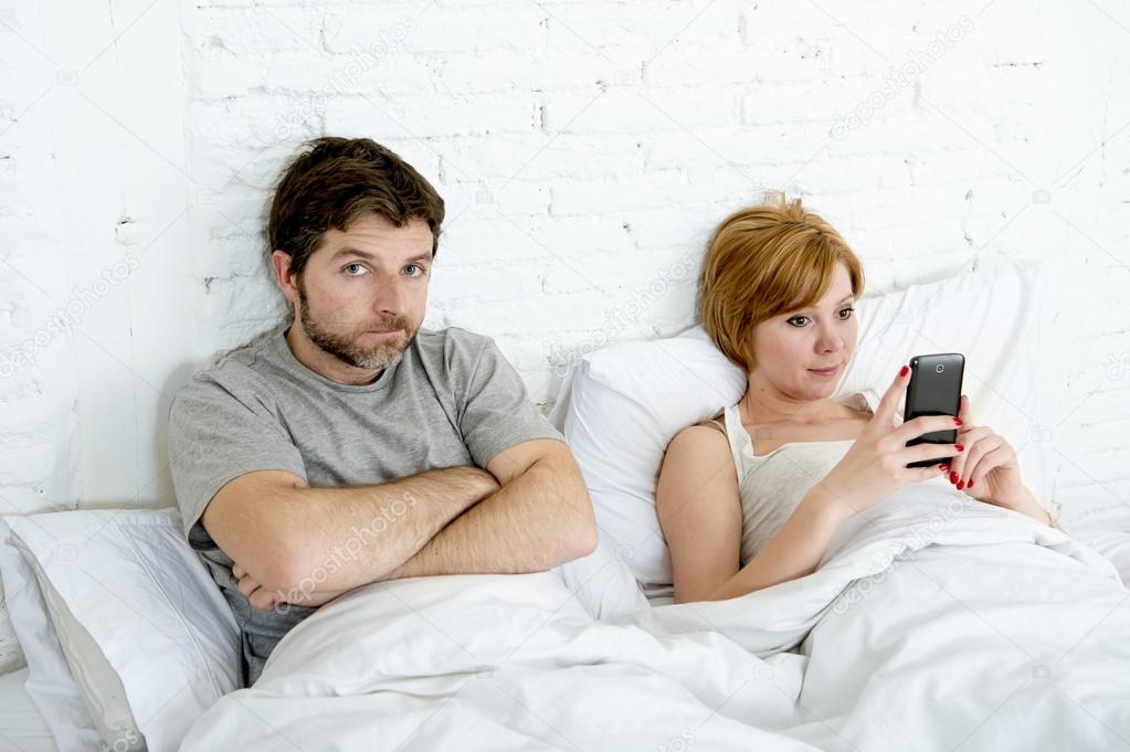 couple in bed husband frustrated upset and unsatisfied while his internet addict wife is using mobile phone