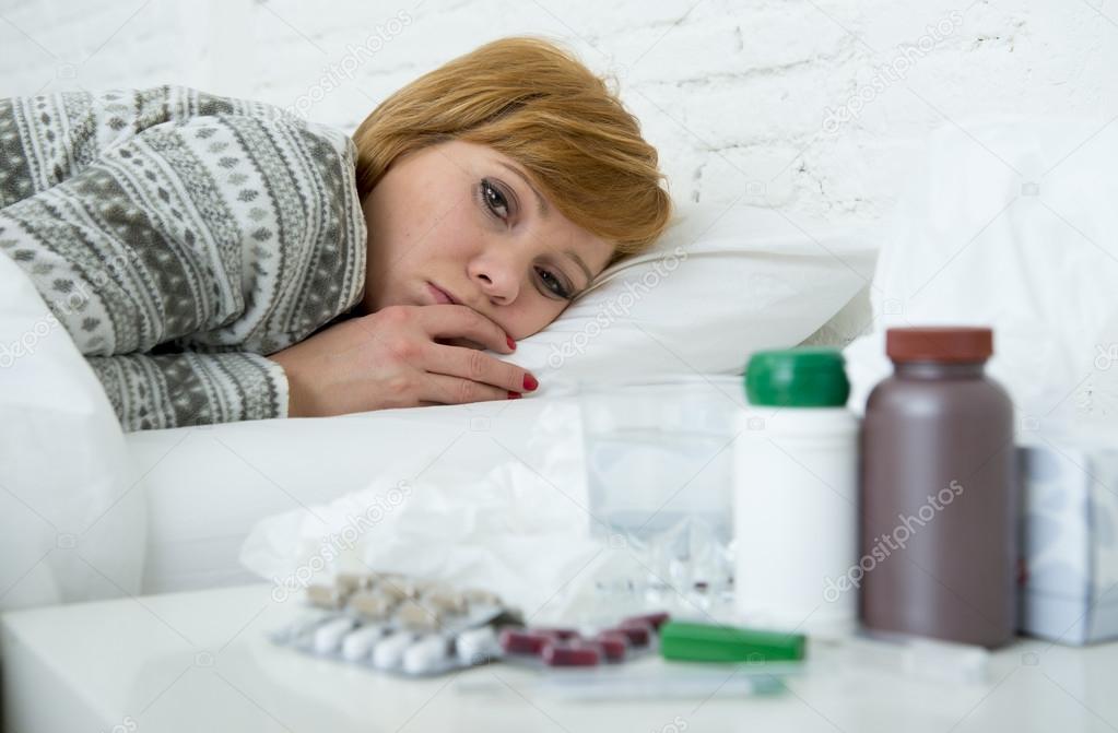  sick woman feeling bad ill lying on bed suffering headache winter cold and flu virus having medicines