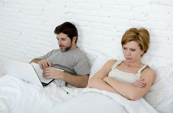 Vonzó nő érzés ideges elégedetlen és csalódott az ágyban a férje, míg a férfi munka figyelmen kívül hagyva neki számítógép laptop — Stock Fotó