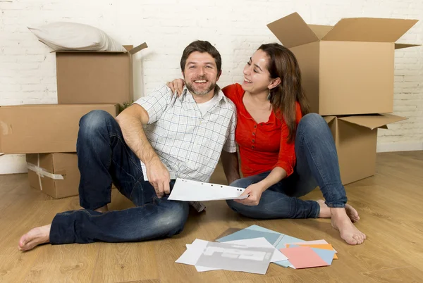 快乐的美国夫妇，坐在地上看蓝图的新房子里移动 — 图库照片