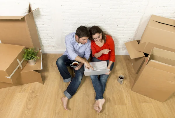 夫妻坐在新房子里，选择家具与电脑笔记本移动的地板上 — 图库照片