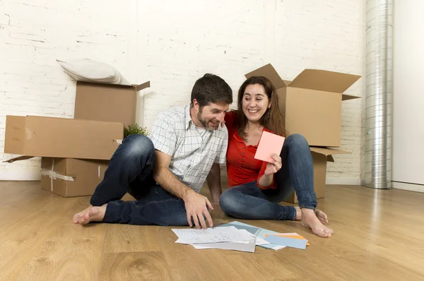 Heureux couple américain assis sur le sol se déplaçant dans une nouvelle maison à la recherche de plans — Photo