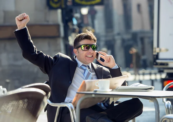 Hombre de negocios desayunando café leyendo periódico hablando feliz en el teléfono móvil haciendo signo de victoria —  Fotos de Stock