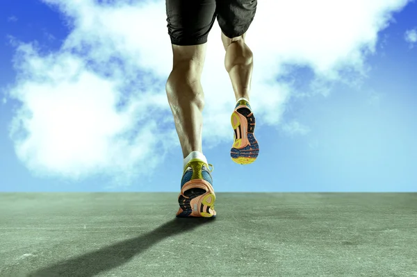 Fuertes piernas atléticas con el músculo de la pantorrilla rasgado del joven deportista corriendo en el camino de asfalto grunge — Foto de Stock