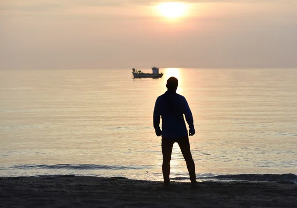 Pemain muda bersiluet melihat ke laut setelah pantai berolahraga saat matahari terbenam — Stok Foto