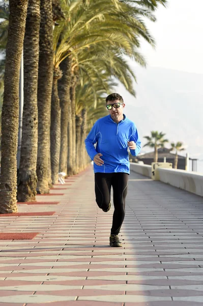 Sportler läuft beim morgendlichen Joggen am Strandpalmenboulevard entlang — Stockfoto