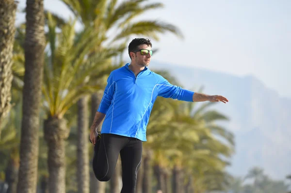 Runner man  stretching at beach palm trees boulevard with sunglasses in morning jog training session — Stock Photo, Image
