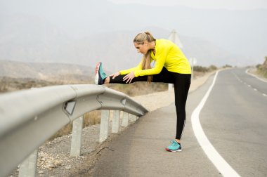 Spor kadın egzersiz kuru çöl manzara ile asfalt yolda zor fitness eğitim oturumunda çalıştırdıktan sonra bacak kas germe