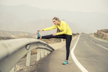 Spor kadın egzersiz kuru çöl manzara ile asfalt yolda zor fitness eğitim oturumunda çalıştırdıktan sonra bacak kas germe