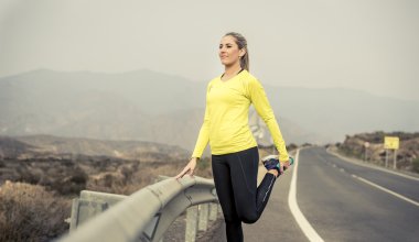 Spor kadın egzersiz kuru çöl manzara ile asfalt yolda zor fitness eğitim oturumunda çalıştırdıktan sonra bacak kas germe
