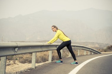 Spor kadın egzersiz kuru çöl manzara ile asfalt yolda zor fitness eğitim oturumunda çalıştırdıktan sonra bacak kas germe
