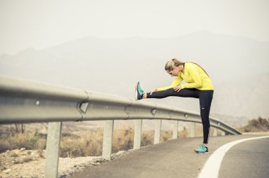 Spor kadın egzersiz kuru çöl manzara ile asfalt yolda zor fitness eğitim oturumunda çalıştırdıktan sonra bacak kas germe