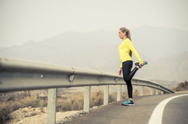 Spor kadın egzersiz kuru çöl manzara ile asfalt yolda zor fitness eğitim oturumunda çalıştırdıktan sonra bacak kas germe
