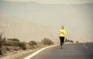 asfalt yol çöl Dağ manzara arka plan ile çalışan genç çekici spor kadın