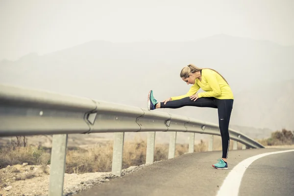 Mujer deporte estiramiento muscular de la pierna después de ejecutar el entrenamiento en carretera de asfalto con el paisaje seco del desierto en sesión de entrenamiento de fitness duro — Foto de Stock
