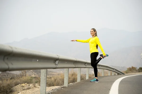 Mujer deporte estiramiento muscular de la pierna después de ejecutar el entrenamiento en carretera de asfalto con el paisaje seco del desierto en sesión de entrenamiento de fitness duro — Foto de Stock